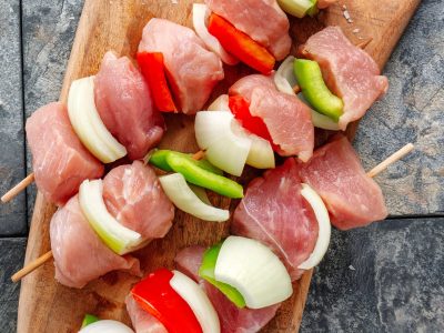 Tasty appetizing raw meat skewers on wooden vintage background. Closeup