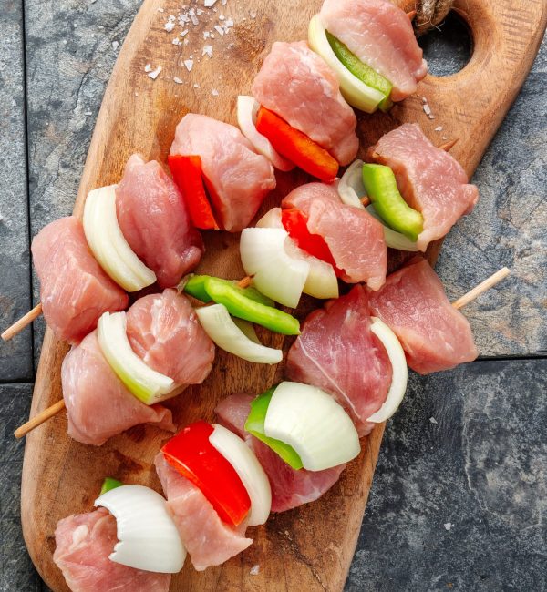 Tasty appetizing raw meat skewers on wooden vintage background. Closeup